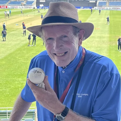 A person wearing a hat and blue shirt is holding a cricket ball