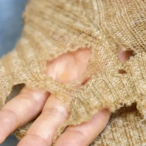 A hand poking through a hole in a jumper