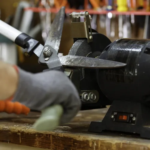 A pair of hedge trimmers being sharpened on a lathe.
