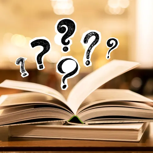 An open book lies flat on a table with floating question marks hovering above