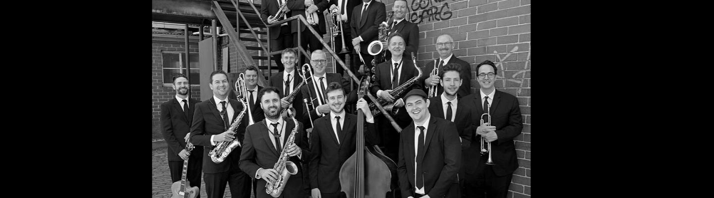 The Jack Earle Big Band posing with their instruments on some stairs.