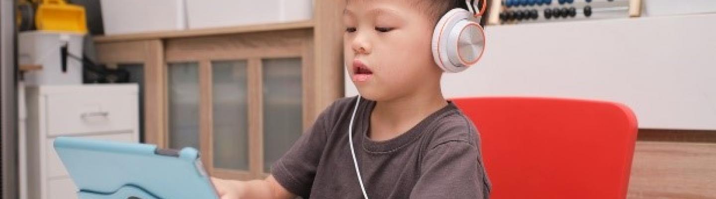 A kid sitting on his iPad with headphones on