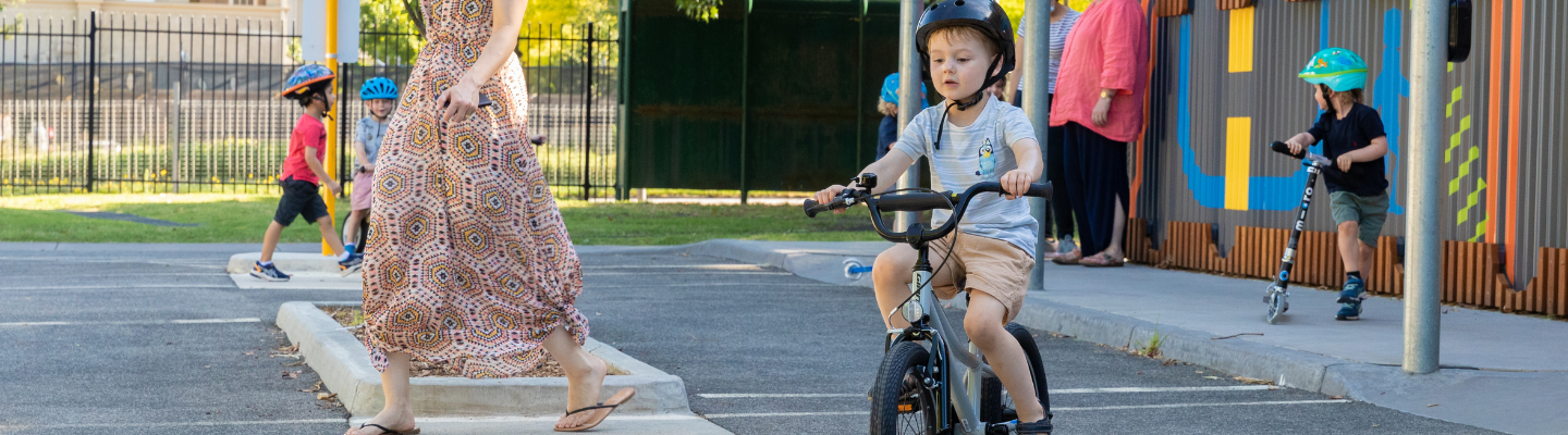 A child wearing a helmet and riding a bike with training wheels