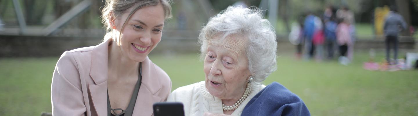 Young woman showing a senior lady how to use her phone 
