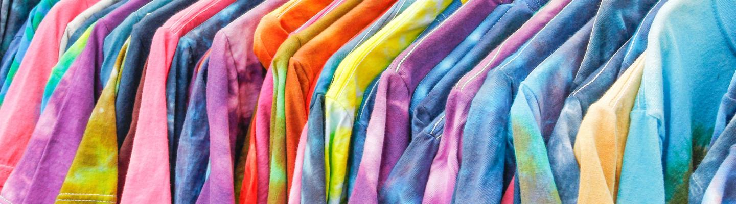 A rack of multicoloured tie-dye t-shirts on hangers