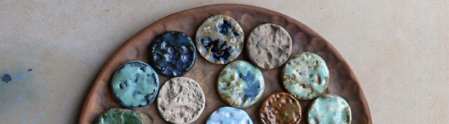 Textured clay brooches with different coloured glazes on a plate