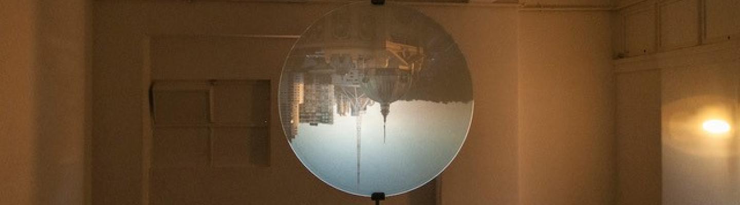 An image of an upside down cityscape is suspended upside down in a dark room