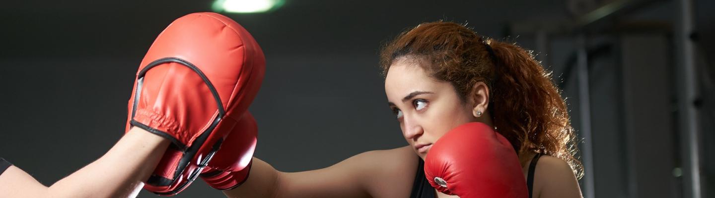 A young woman in boxing gloves sparring with an unseen person