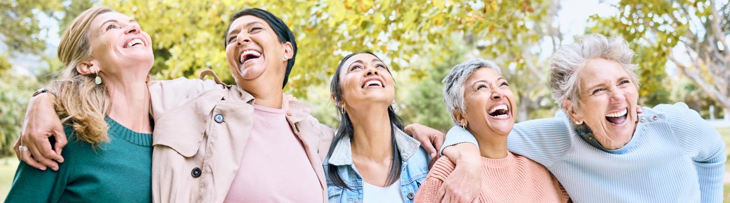Five older women lined up in a park laughing