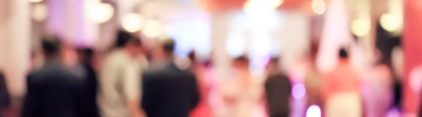 Deliberately blurred image of people mingling in a brightly lit room