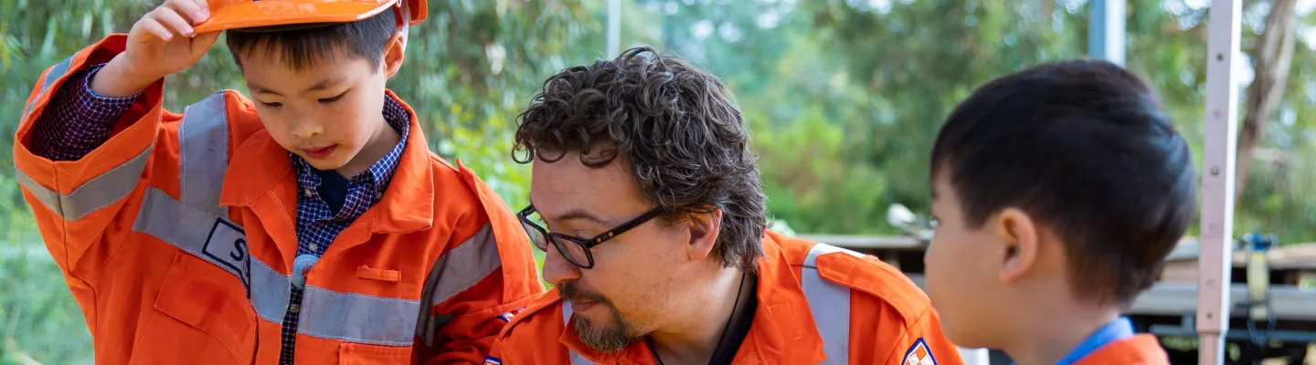 an adult and 2 small children wearing high-vis safety outfits
