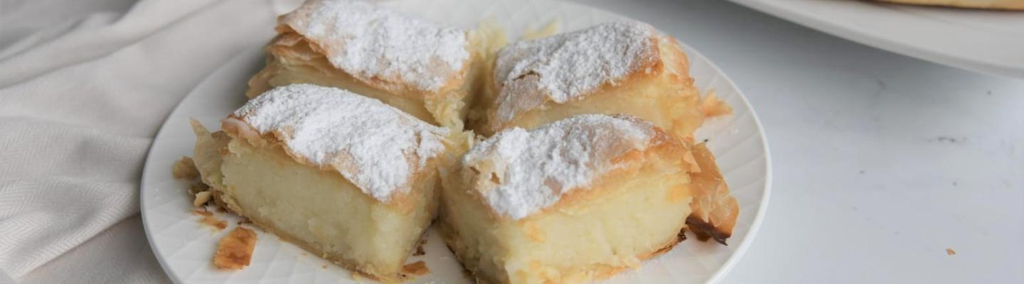 White plate with custard squares dusted with icing sugar