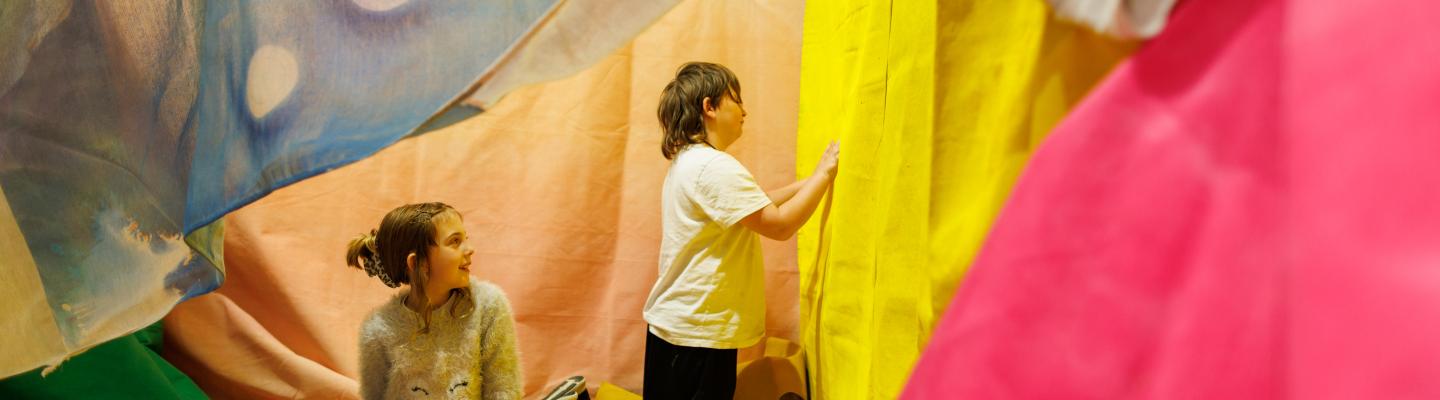 Two children explore a colourful art installation