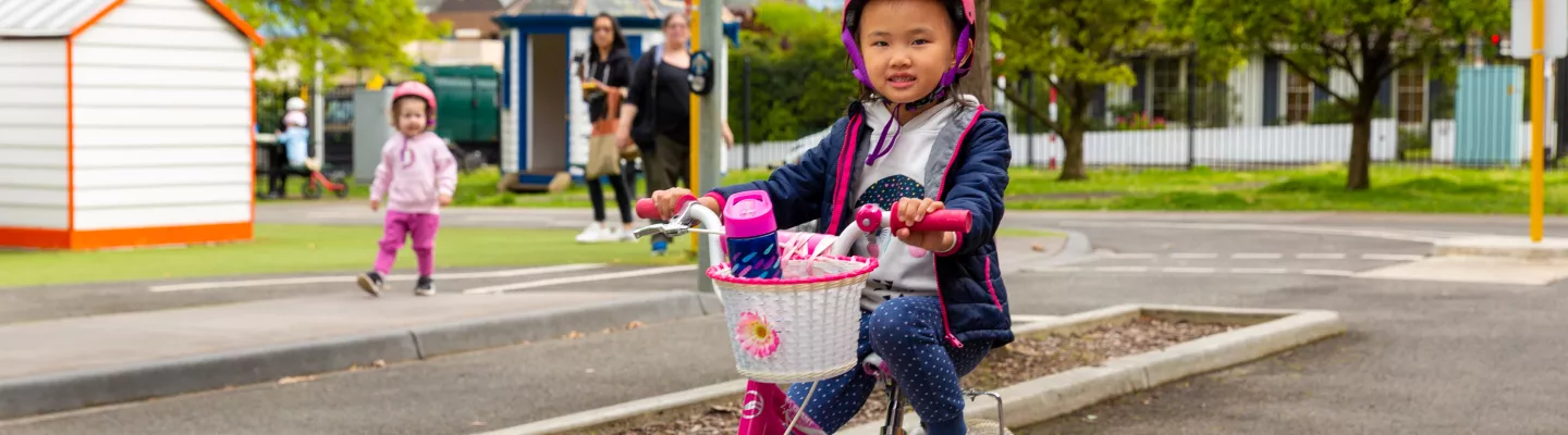Child aged about 5 years riding a bike with training wheels at Kew Traffic School
