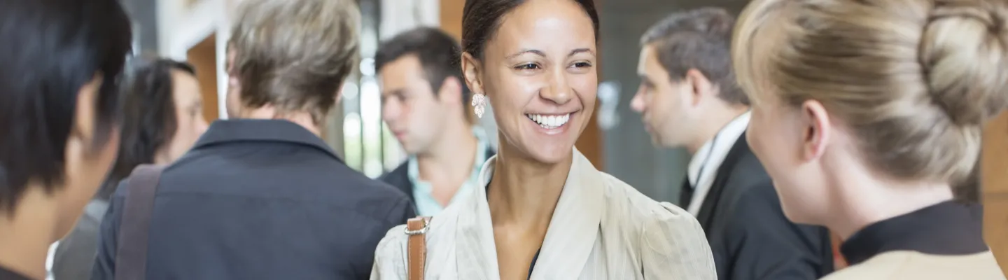 crowded room with young woman talking to another woman with back to camera
