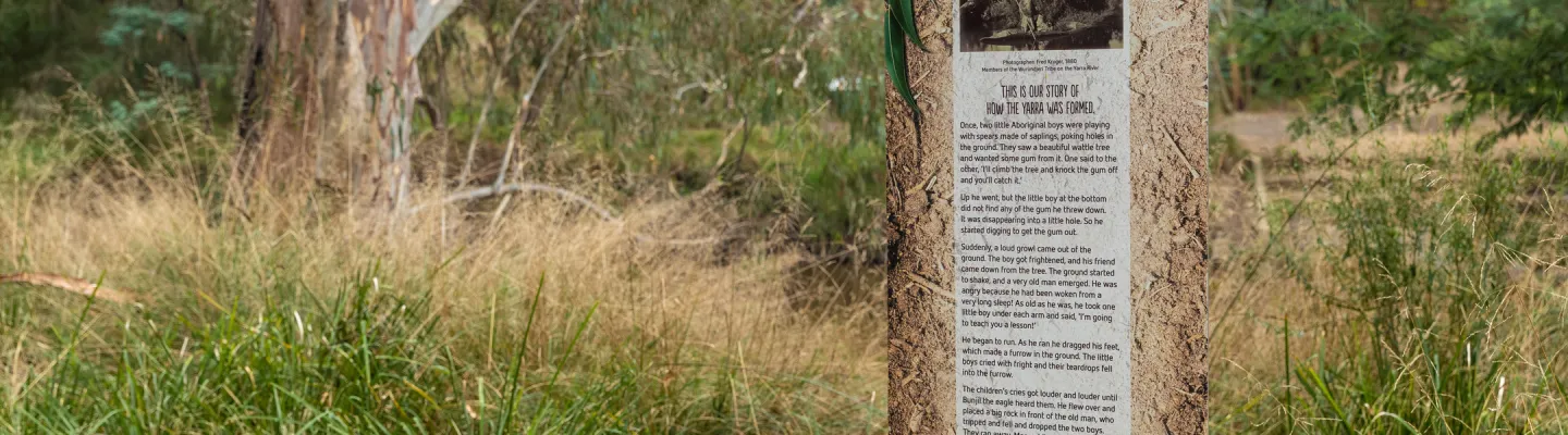 A trail maker with descriptive text along a grassy path in bushland