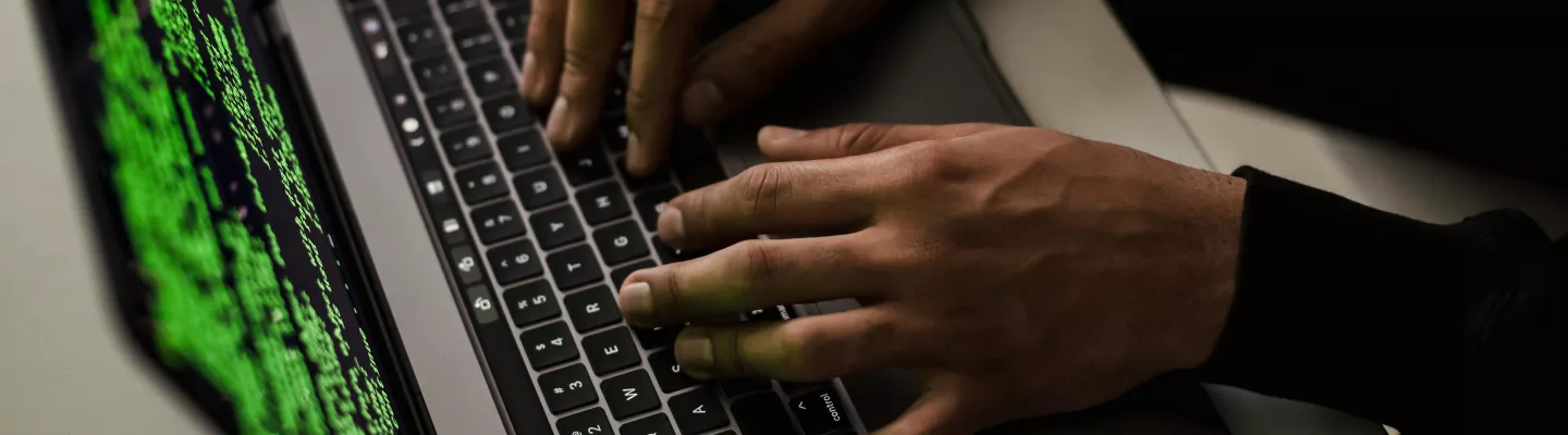 A persons hands typing on a laptop