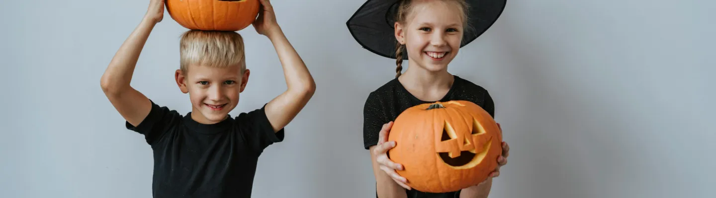 Two children holding Halloween pumpkins