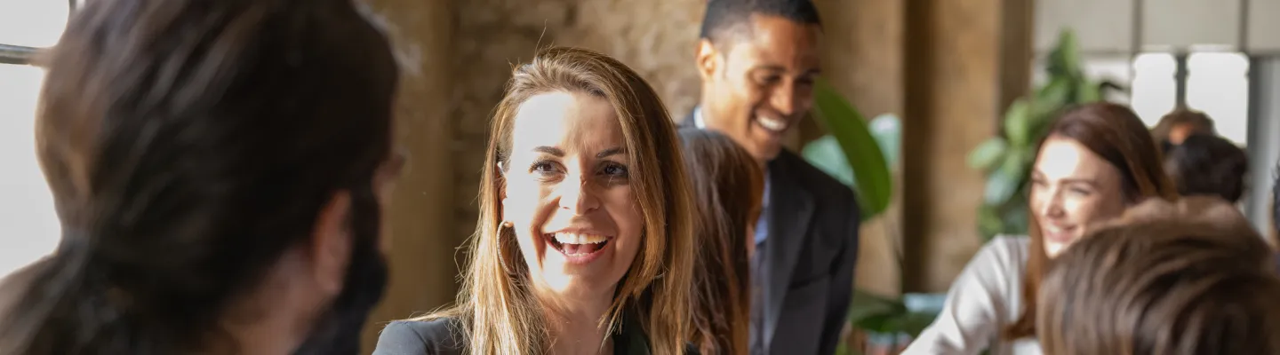 A women is smiling and shaking the hands of a person in front of her