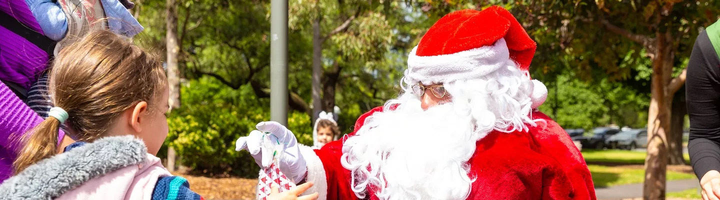 Santa in his red and white outfit handing out lolly bags