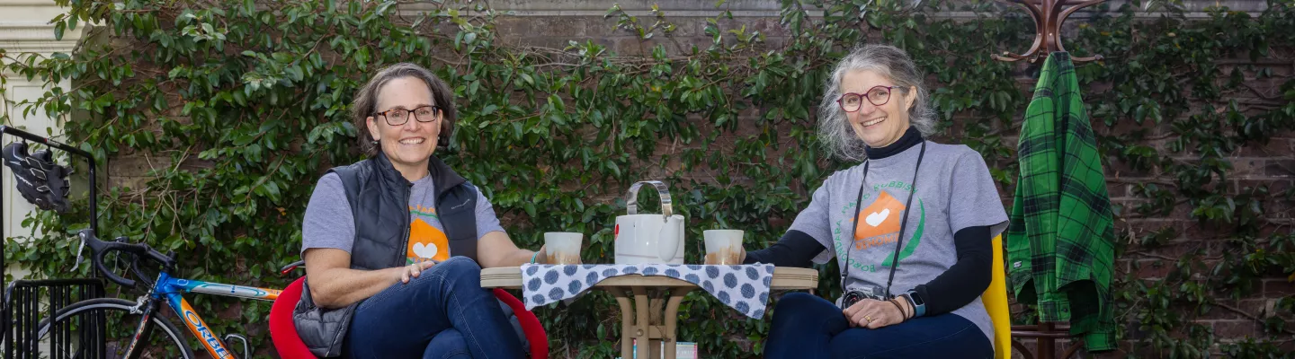 Two people sitting at a table surrounded collected reusable items