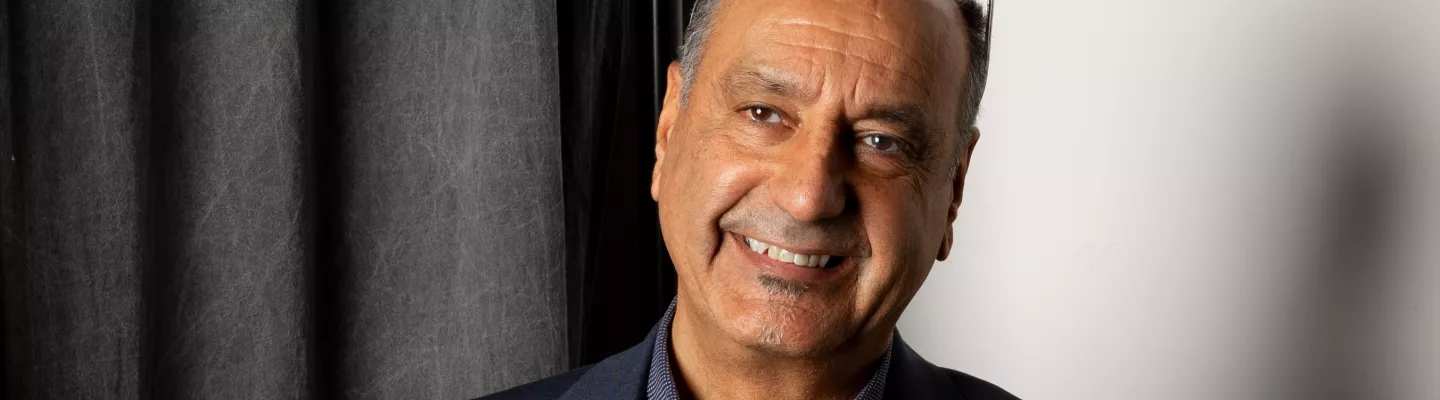 A photo of George Petrou in casual suit attire with glasses atop his head