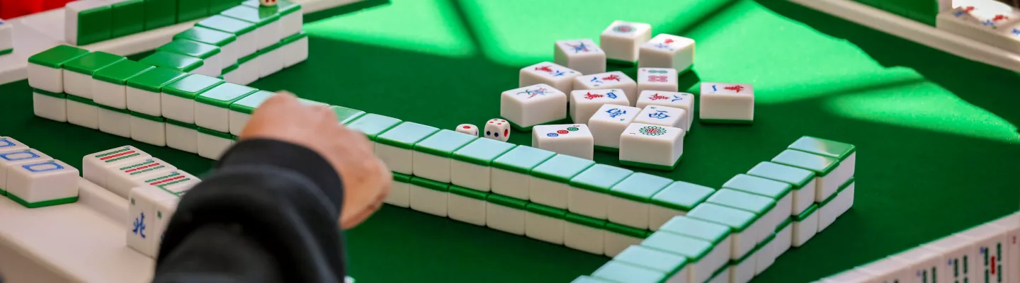 A Mahjong game board with a hand picking up a tile