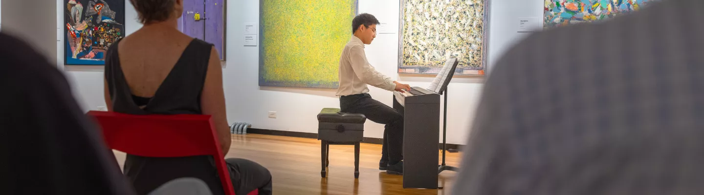 Man playing an upright piano in a gallery