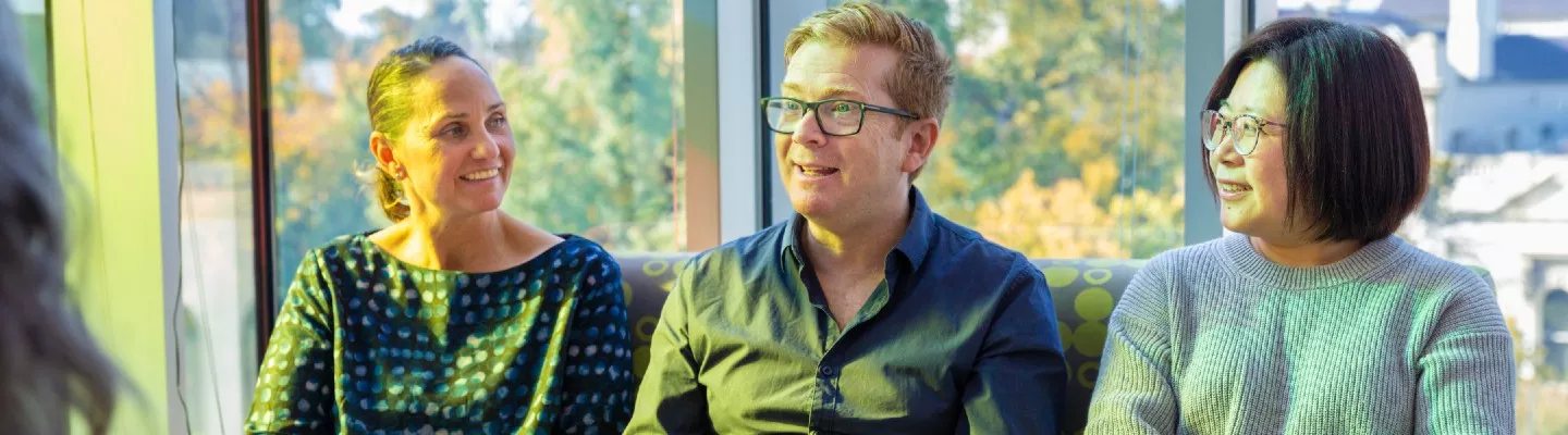 Three people sitting in a row chatting to each other at a workshop