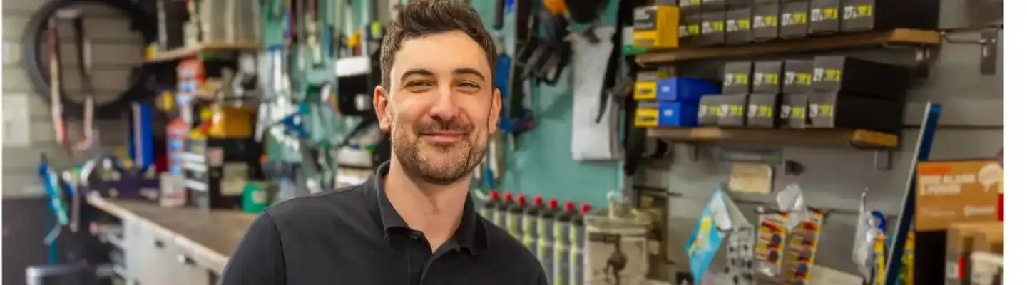Smiling man standing behind a bike mechanic's counter