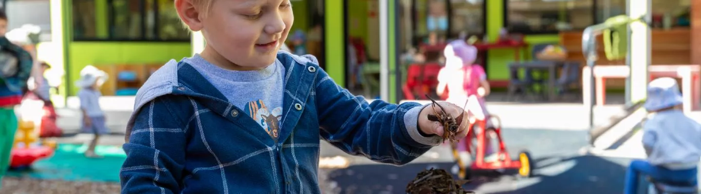 Young child playing with mud at a kindergarten outdoor area