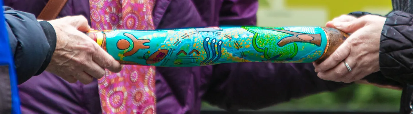Two people holding a thick stick covered in illustrations