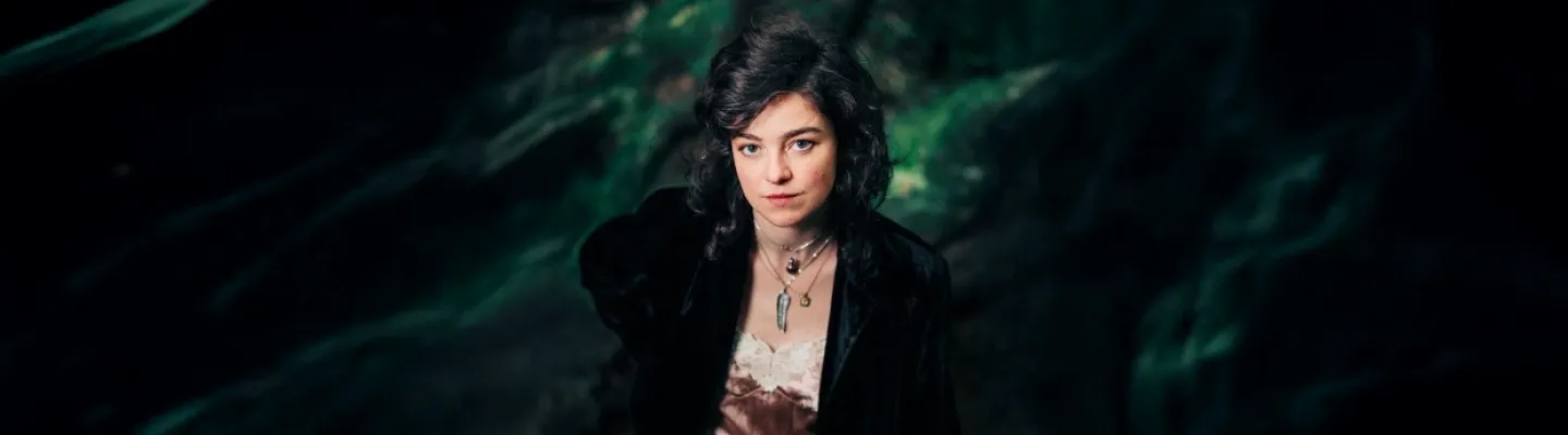 Ingrid Saker, lead singer of Ingrid and the Ministers, standing in front of a green and black background.