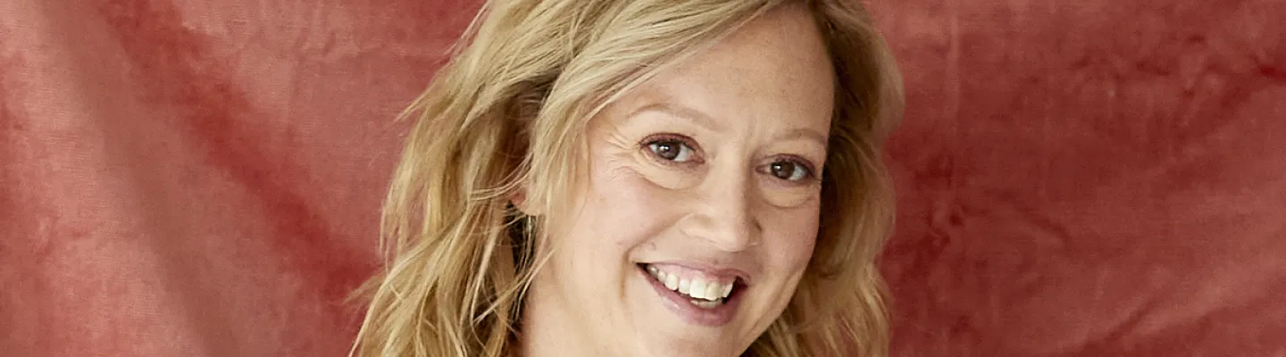 Author looking directly at camera, smiling with crossed arms. She is wearing a mint green shirt.