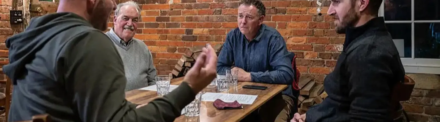 Four men sitting around a table having a conversation