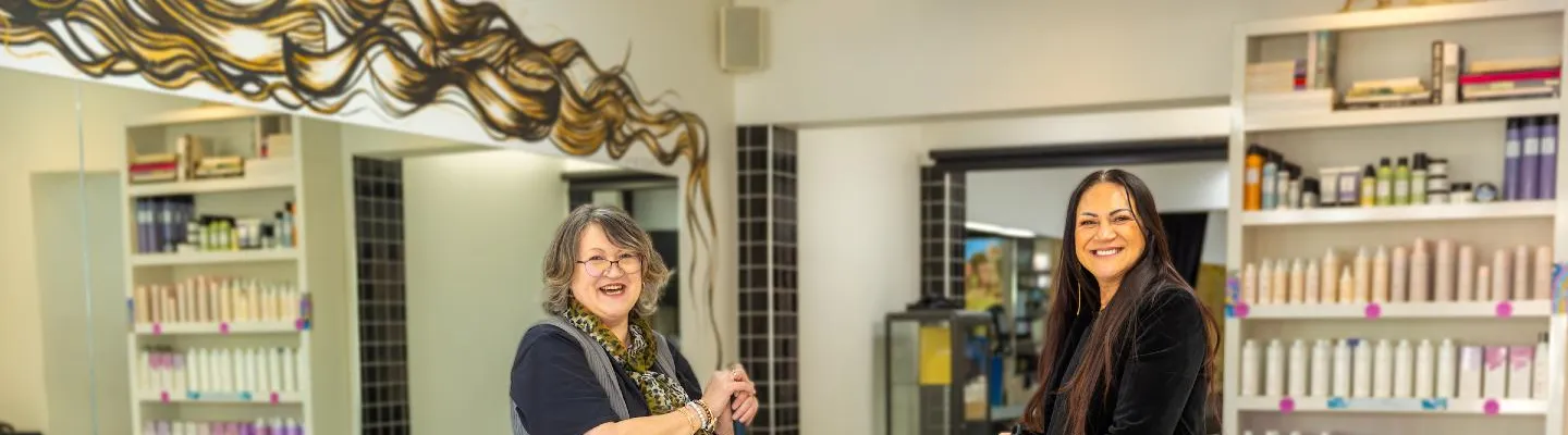 Two women holding brooms in a beauty salon