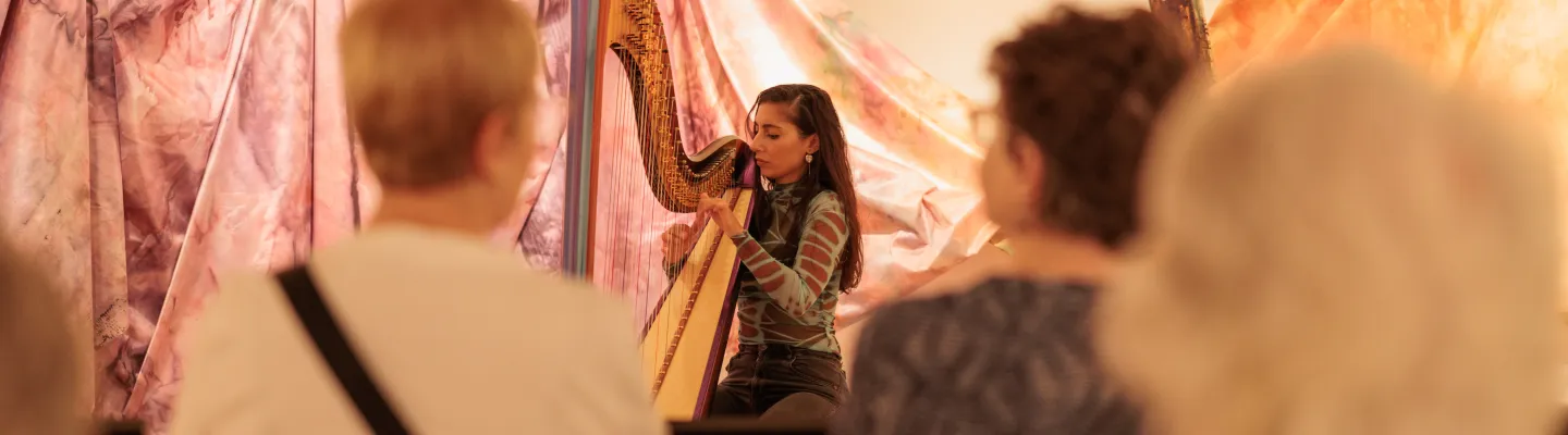 a woman plays harp in front of a seated audience