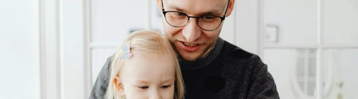 A father and young daughter play at the table  with wooden blocks.