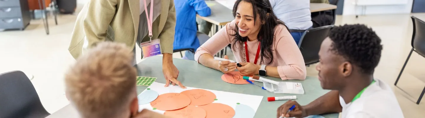 Four people sitting around a table making a circular economy diagram with different coloured papers