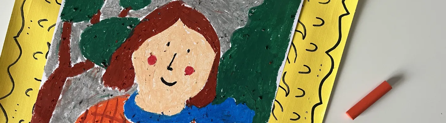 The image shows a colourful drawing placed on top of a yellow piece of paper with decorative patterns. The drawing itself features an abstract representation of a person with red cheeks, brown hair, blue scarf, and red checkered clothing. The background consists of gray sky with some large trees. There are also two crayons lying next to the drawing, one blue and one red.