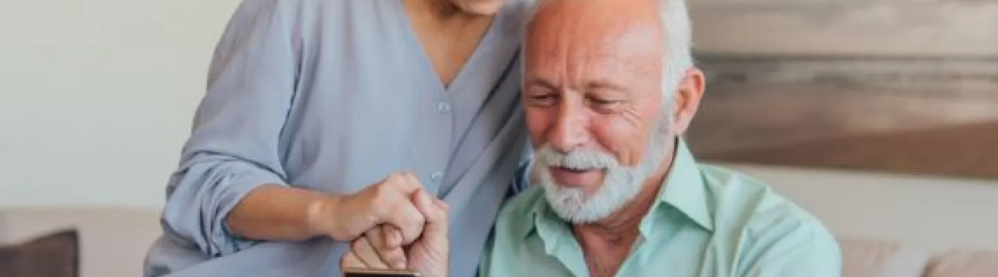 Older couple are looking at something on a mobile phone. 