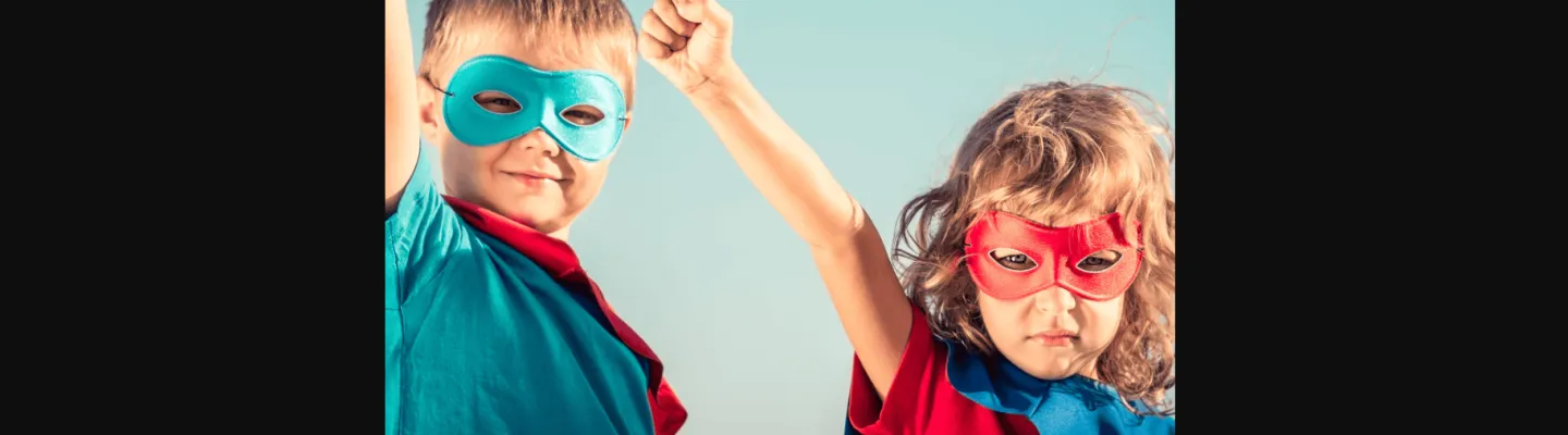 Two children dressed as superheroes, each posed as a super hero with one arm in the air.
