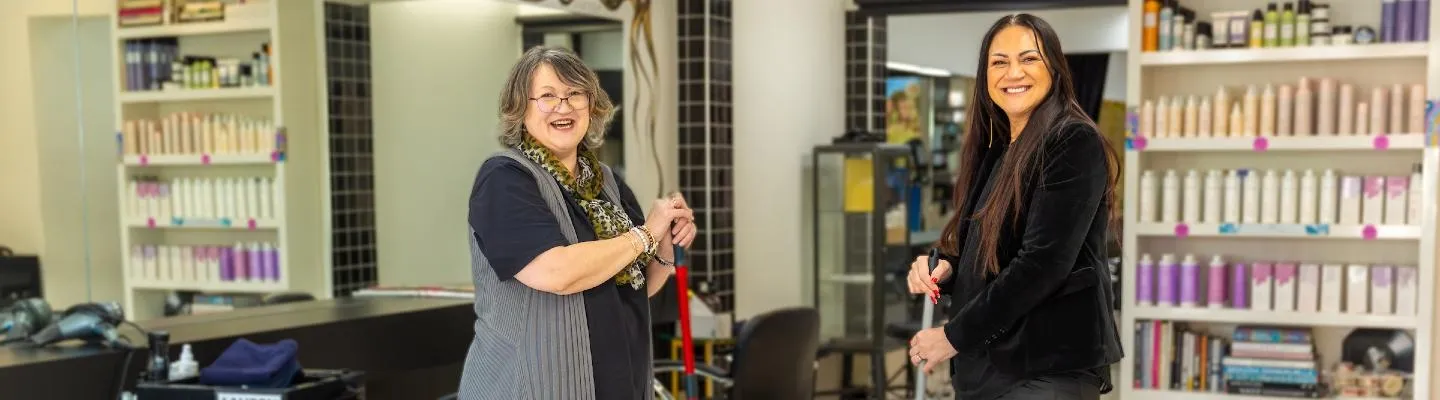 Two women holding brooms in a beauty salon