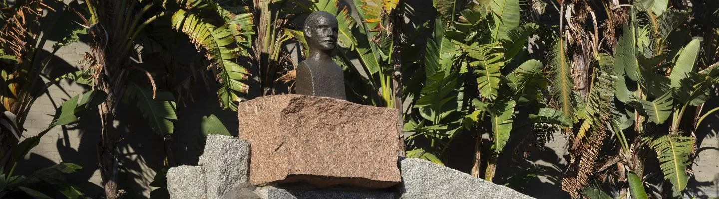 A photograph of a bronze bust on top of a large base of stones. 