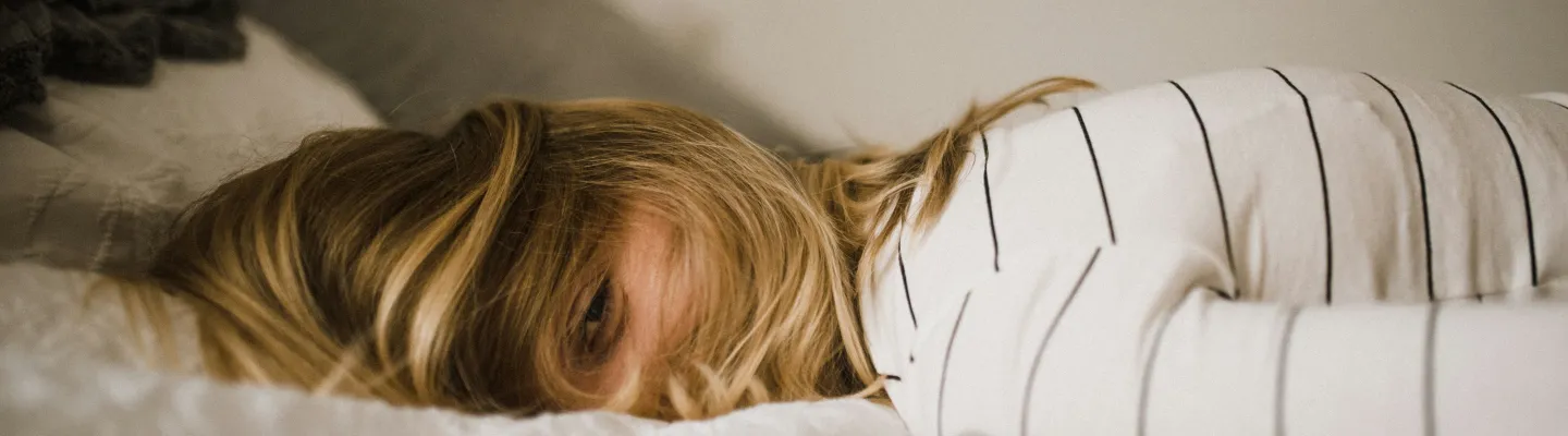 Woman with hair partially covering her face is lying on a bed
