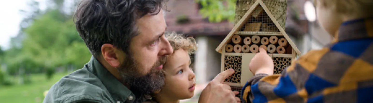 A family outside looking at a bird house.