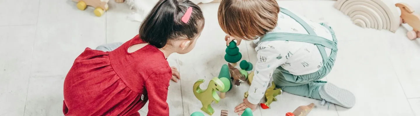 two young children playing with toys on the floor of a white room