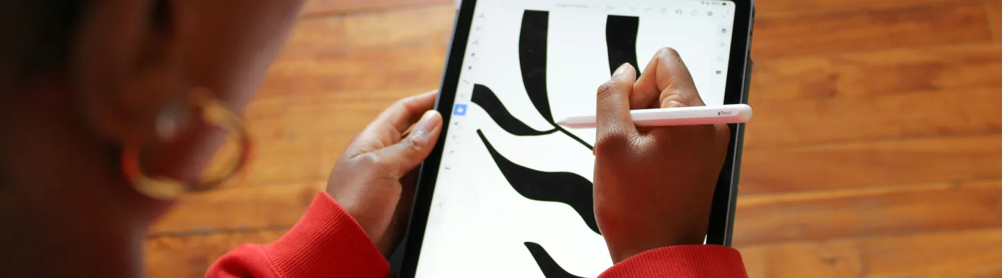 A person is holding a tablet and drawing stylus while they draw black lines on the tablet.