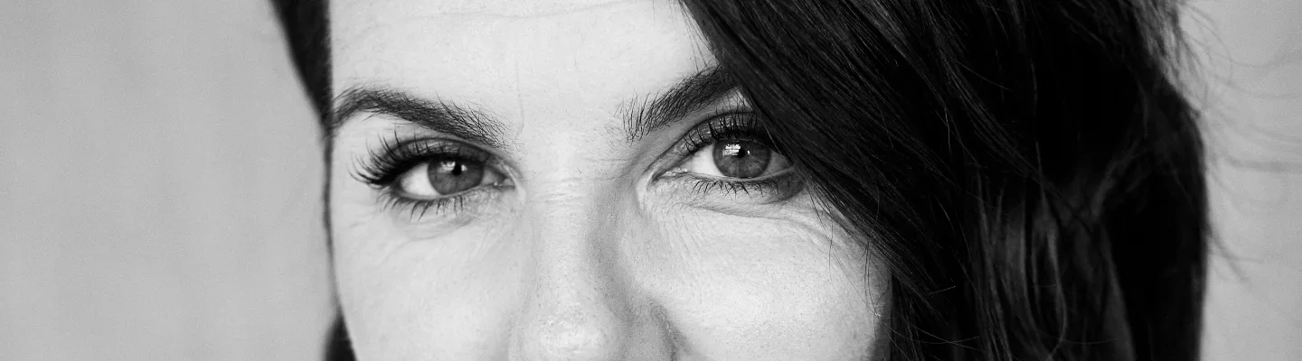 Close up image of woman with dark hair staring straight ahead
