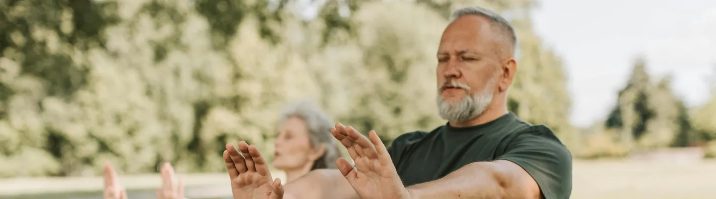 A man and woman are standing in a park with their arms stretched out in front of them.